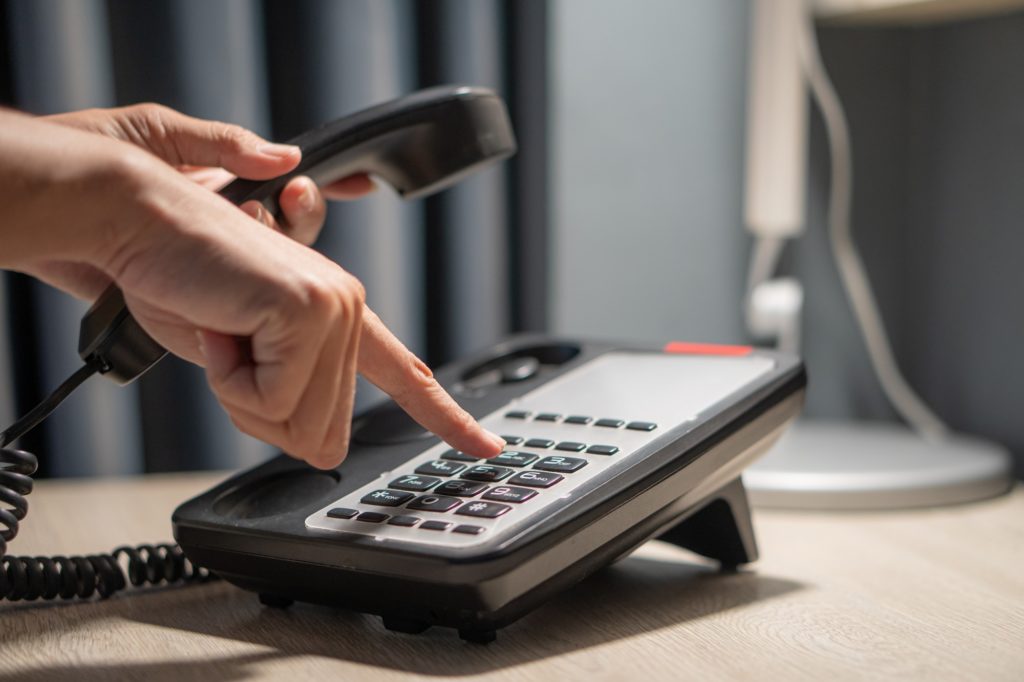 Photo of hands pressing button on black telephone